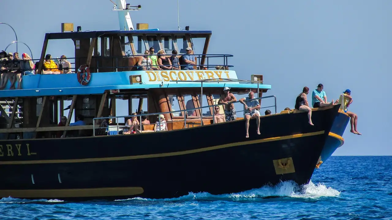 A large two-deck boat at sea with passengers on the upper deck