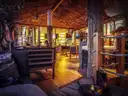 The wooden interior of an empty bar with stools and lanterns