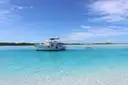 A white motor yacht anchored in clear, shallow turquoise water
