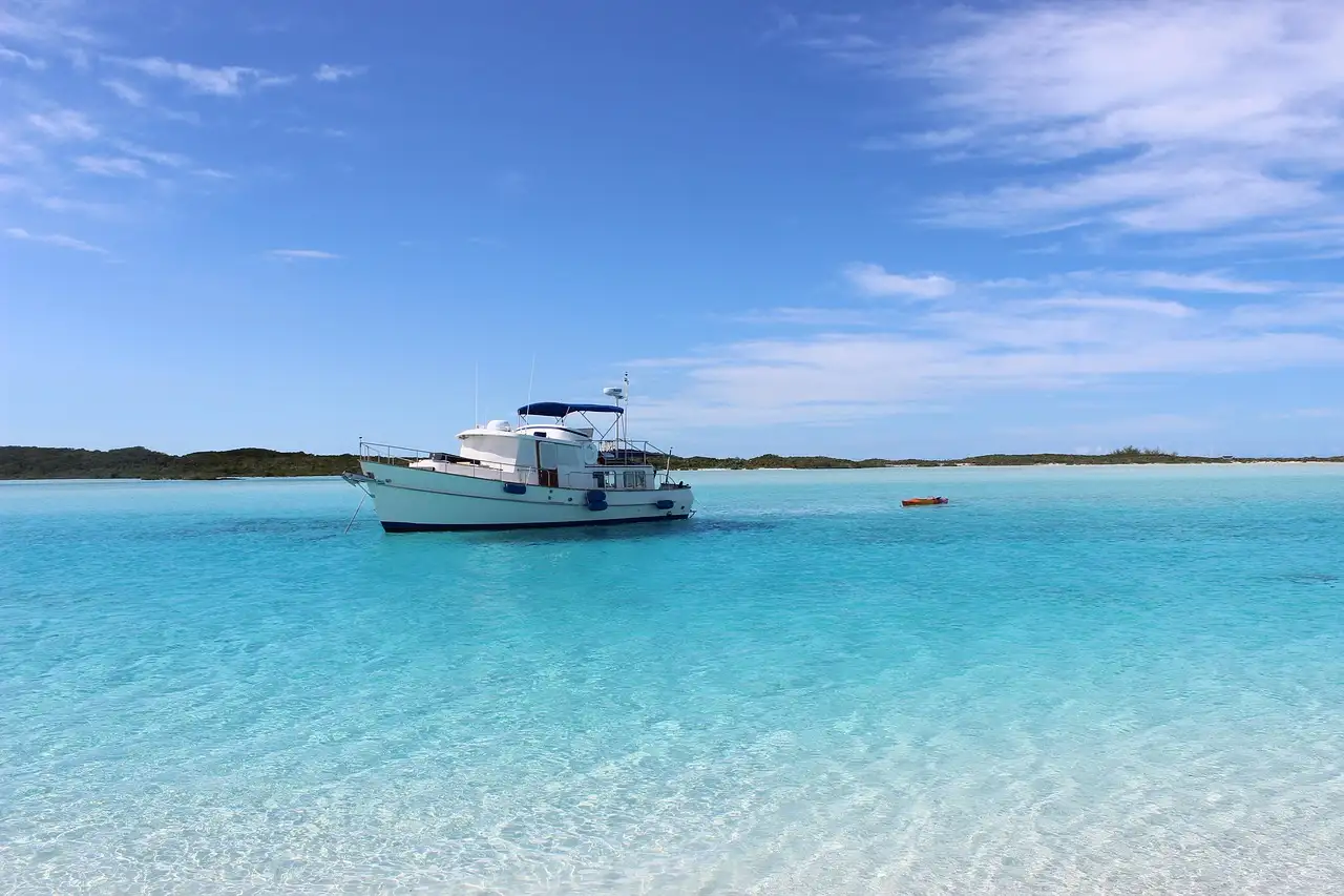 A white motor yacht anchored in clear, shallow turquoise water